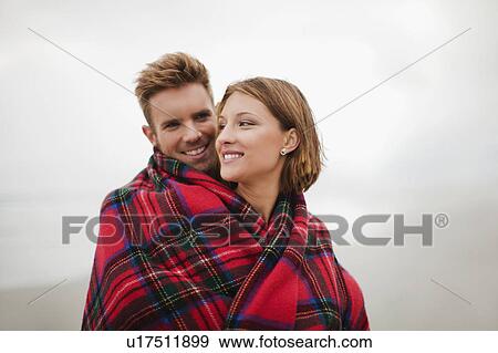 Couple wrapped in blanket on beach View Large Photo Image Stock Photo - Couple wrapped in blanket on beach. Fotosearch