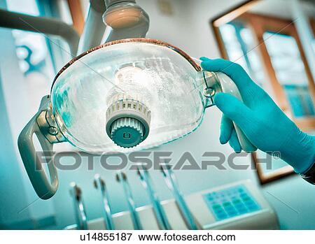 Stock Photo - Dentist adjusting lamp in office. Fotosearch