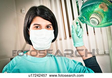 Dentist adjusting lamp in office View Large Photo Image Stock Photo - Dentist adjusting lamp in office. Fotosearch