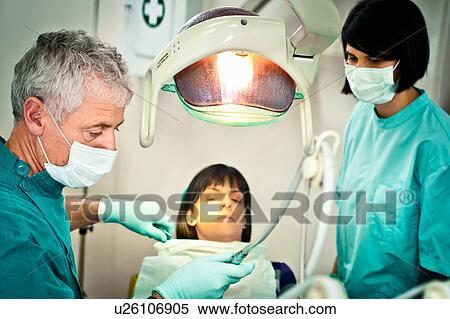 Stock Photography - Dentist and assistant working in office. Fotosearch
