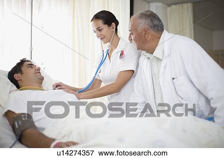 Doctor and nurse tending to patient View Large Photo Image Stock Photo - Doctor and nurse tending to patient. Fotosearch