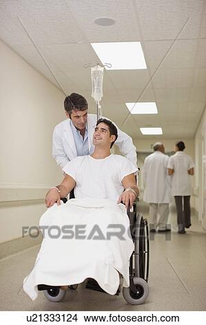 Picture - Doctor pushing patient in wheelchair. Fotosearch