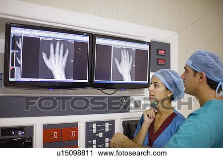 Stock Image - Doctors examining x-ray of hand. Fotosearch