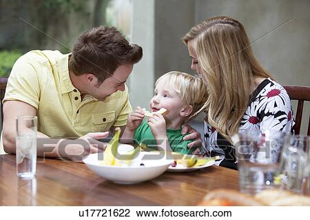Stock Image - Family eating a meal together at home. Fotosearch