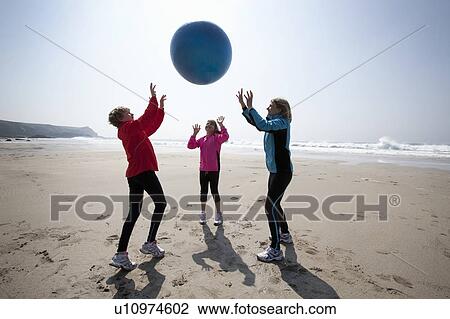 Stock Image - Family playing with ball on beach. Fotosearch