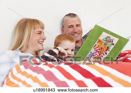Family reading book together in bed View Large Photo Image Stock Image - Family reading book together in bed. Fotosearch