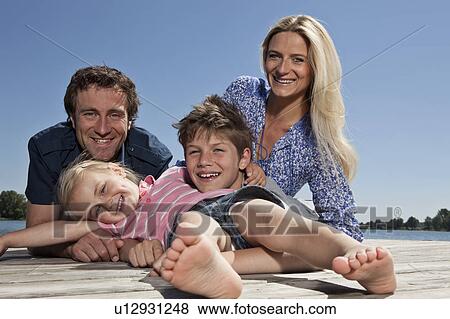 Stock Photo - Family relaxing together on dock. Fotosearch