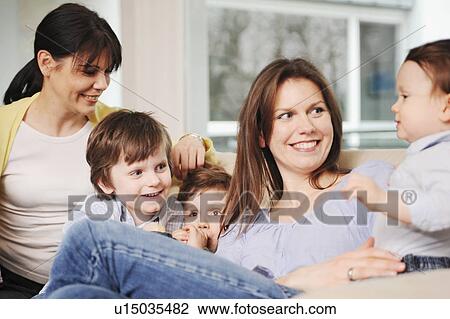 Stock Image - Family sitting on sofa together. Fotosearch
