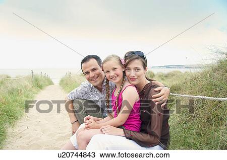 Stock Image - Family sitting together on beach. Fotosearch