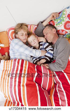 Stock Photography - Family sleeping together in bed. Fotosearch