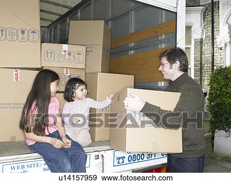 Stock Photo - Family unpacking boxes from moving van. Fotosearch