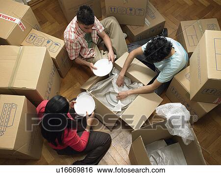 Stock Photograph - Family unpacking cardboard boxes. Fotosearch