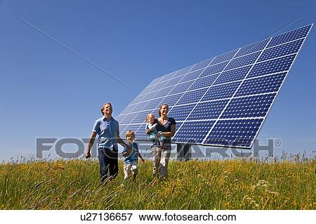 Stock Photo - Family walking in field by solar panel. Fotosearch