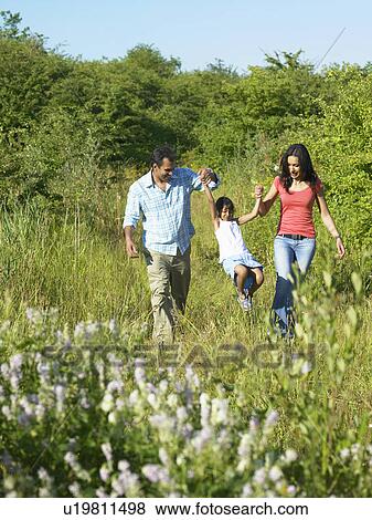 Stock Photo - Family walking in field of flowers. Fotosearch