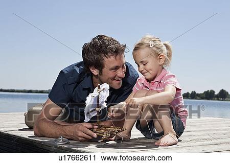 Stock Image - Father and daughter playing on dock. Fotosearch