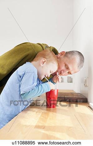 Stock Photography - Father and son drinking with straws. Fotosearch