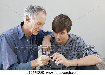 Stock Image - Father and son examining tool together. Fotosearch