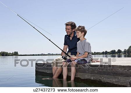 Stock Image - Father and son fishing together on dock. Fotosearch