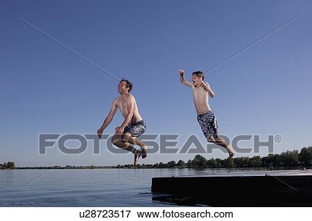 Stock Photo - Father and son jumping into lake. Fotosearch