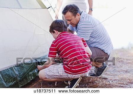 Stock Image - Father and son pitching a tent together. Fotosearch