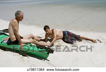 Picture - Father and son relaxing on beach. Fotosearch
