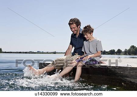 Father and son relaxing together on dock View Large Photo Image Stock Photo - Father and son relaxing together on dock. Fotosearch