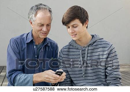 Stock Photo - Father and son using cell phone together. Fotosearch
