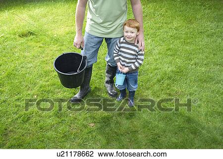Stock Image - Father and son with buckets in backyard. Fotosearch