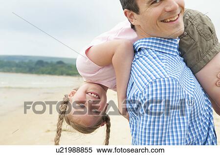 Stock Photography - Father carrying daughter on beach. Fotosearch