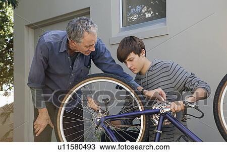 Father helping son repair bicycle View Large Photo Image Stock Image - Father helping son repair bicycle. Fotosearch