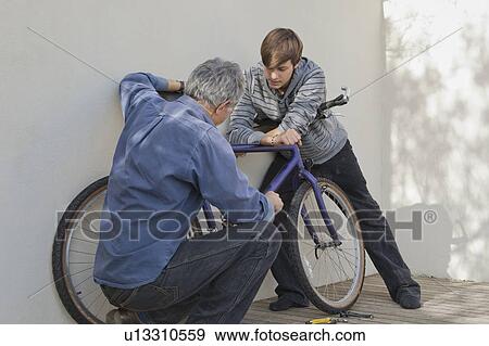 Stock Photo - Father helping son repair bicycle. Fotosearch
