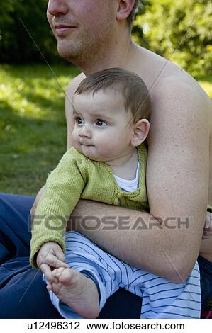 Stock Image - Father holding baby boy outdoors. Fotosearch