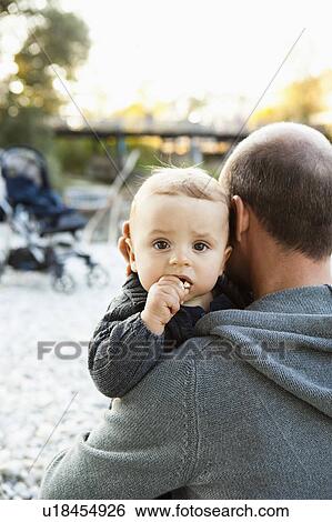 Stock Photograph - Father holding baby outdoors. Fotosearch