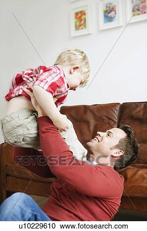 Father playing with son in living room View Large Photo Image Stock Image - Father playing with son in living room. Fotosearch