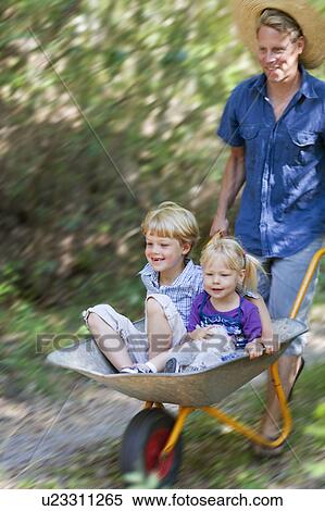 Father pushing children in wheelbarrow View Large Photo Image Stock Photography - Father pushing children in wheelbarrow. Fotosearch