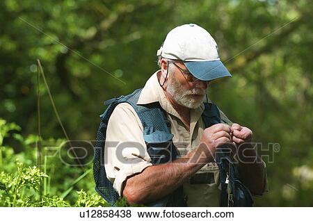 Fisherman tying on fly View Large Photo Image Stock Photo - Fisherman tying on fly. Fotosearch
