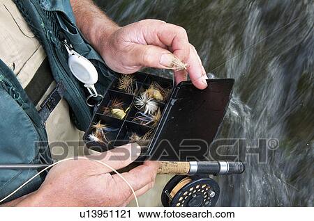 Fly fisherman holding fly box in river View Large Photo Image Stock Image - Fly fisherman holding fly box in river. Fotosearch