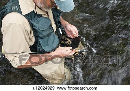 Fly fisherman holding fly box in river View Large Photo Image Stock Photo - Fly fisherman holding fly box in river. Fotosearch