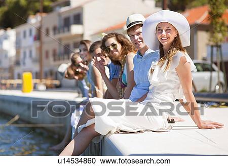Stock Image - Friends sitting on urban dock. Fotosearch