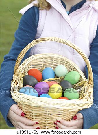 Stock Photography - Girl carrying basket of Easter eggs. Fotosearch