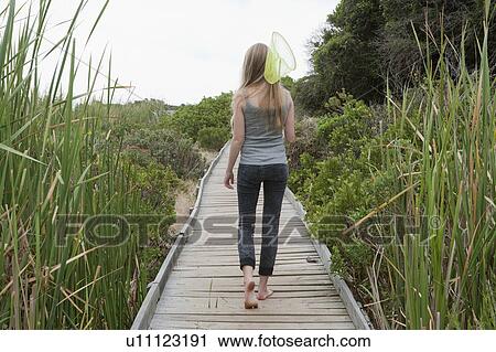 Girl carrying net on wooden walkway View Large Photo Image Stock Image - Girl carrying net on wooden walkway. Fotosearch