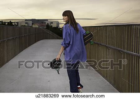 Girl carrying skateboard on walkway View Large Photo Image Stock Photo - Girl carrying skateboard on walkway. Fotosearch