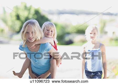 Girl carrying younger sister piggyback View Large Photo Image Stock Image - Girl carrying younger sister piggyback. Fotosearch