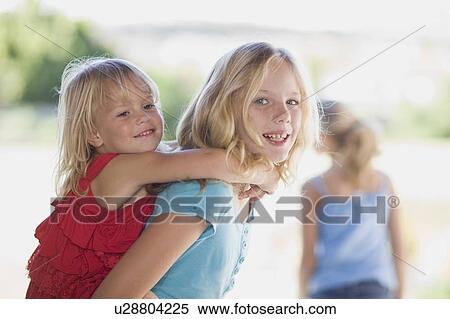 Girl carrying younger sister piggyback View Large Photo Image Stock Photography - Girl carrying younger sister piggyback. Fotosearch