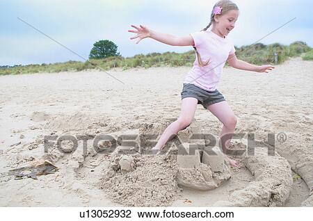 Girl destroying sand castle on beach View Large Photo Image Stock Image - Girl destroying sand castle on beach. Fotosearch