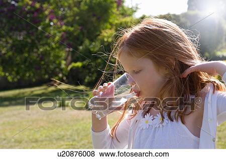 Girl drinking glass of water in backyard View Large Photo Image Stock Photo - Girl drinking glass of water in backyard. Fotosearch