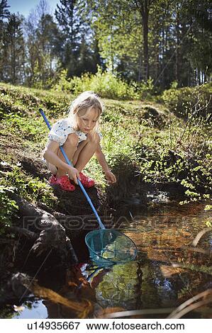 Girl fishing with net in creek View Large Photo Image Stock Photo - Girl fishing with net in creek. Fotosearch