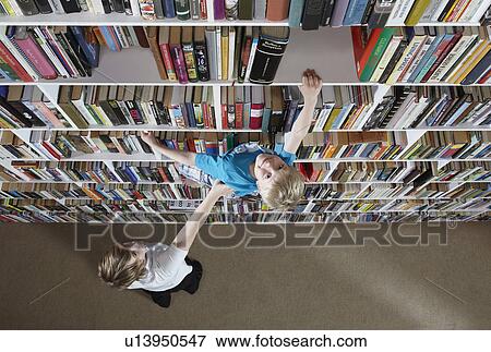 Girl helping boy climb bookshelves View Large Photo Image Stock Photo - Girl helping boy climb bookshelves. Fotosearch