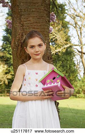 Stock Photo - Girl holding birdhouse in backyard. Fotosearch