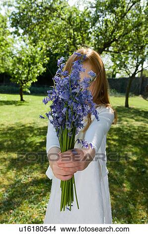 Picture - Girl holding flowers in backyard. Fotosearch